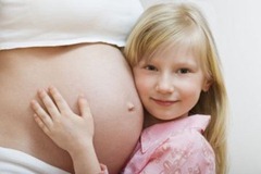 Portrait of girl (7-9) hugging pregnant mother's belly